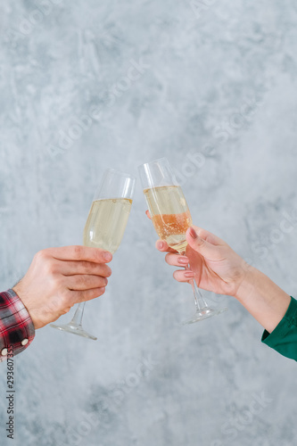 Romantic date. Cropped shot of couple clanging champagne glasses over blur textured gray wall background. Copy space.