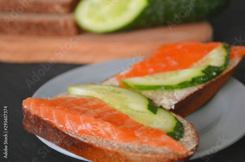 Healthy breakfast. sandwich with salmon and cucumber, brown bread and butter on a wooden background.