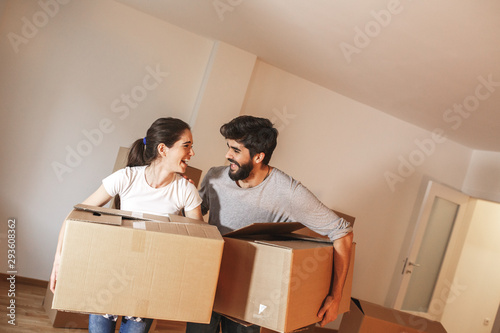 Young couple carrying big cardboard full of home essentials into a new home.Moving house concept.