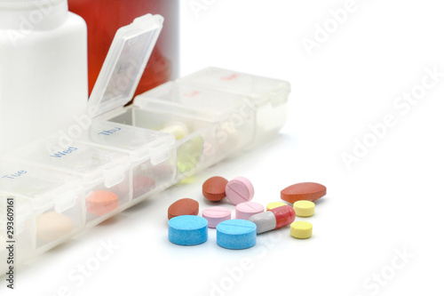 Close up of various pills with medicine box and drug bottle on white background. Daily vitamins and supplements dosage routine concept. With copy space and blank for text