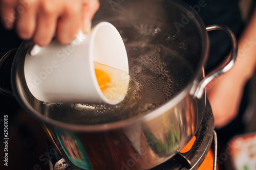 Chef pouring egg in a boiling water photo