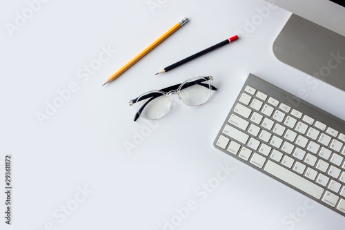 business concept. top view of office desk workspace with desktop computer, pen, keyboard, glasses and hot on white table background
