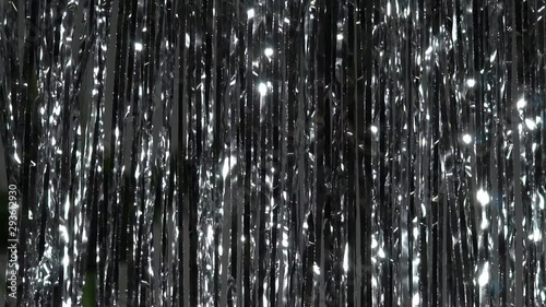 Silver rain from tinsel. Dynamic background in shining lights and sparkling particles. Beautiful silver background with shiny silver glitter sparkles. Festive mood. Christmas or holiday theme