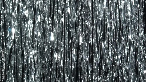 Silver rain from tinsel. Dynamic background in shining lights and sparkling particles. Beautiful silver background with shiny silver glitter sparkles. Festive mood. Christmas or holiday theme