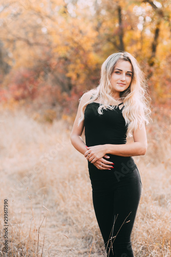 Beautiful attractive girl posing in autumn forest in black pants and t-shirt with beautiful white hair