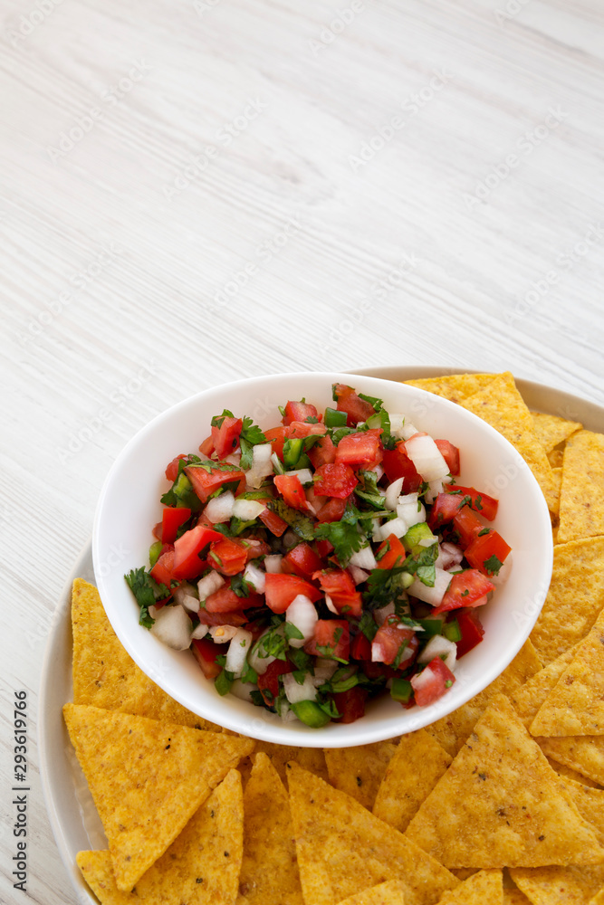 Pico de Gallo with gluten free tortilla chips on a white wooden table, side view. Copy space. Pico de Gallo with gluten free tortilla chips on a white wooden table, side view. Copy space.