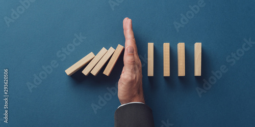 Business crisis manager stopping falling dominos from collapsing photo