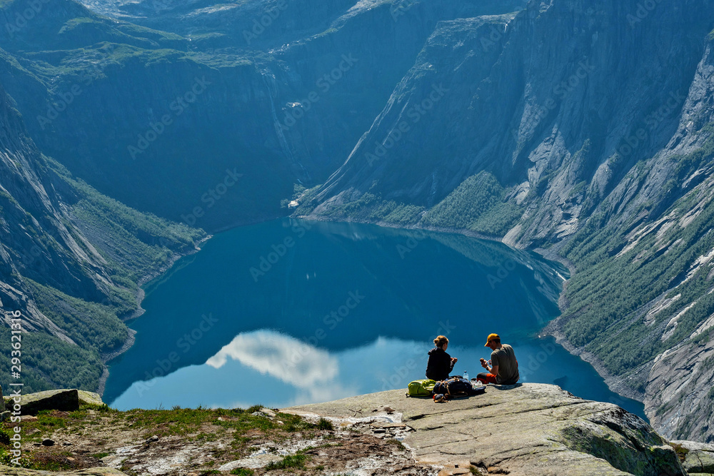 Mountain lake landscape view, Norway. Couple sitting on the shore of Ringedalsvatnet lake, way to Trolltunga rock.