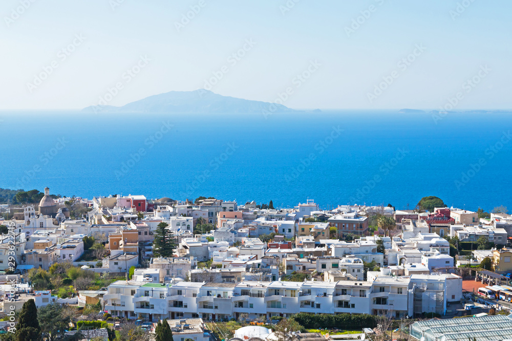 Town of Capri, Italy with white houses, blue sky and blue water. View of Mount Vesuvius