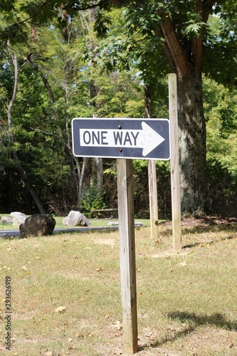 The black and white one way sign on the side of the road.