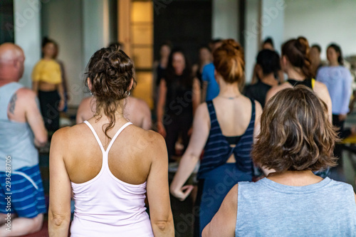 Fototapeta Naklejka Na Ścianę i Meble -  Diverse group of people in yoga class. Spiritual people of all ages and backgrounds are seen kneeling inside a yoga club as they partake in 108 salutations to the sun. Traditional Hindu practice.