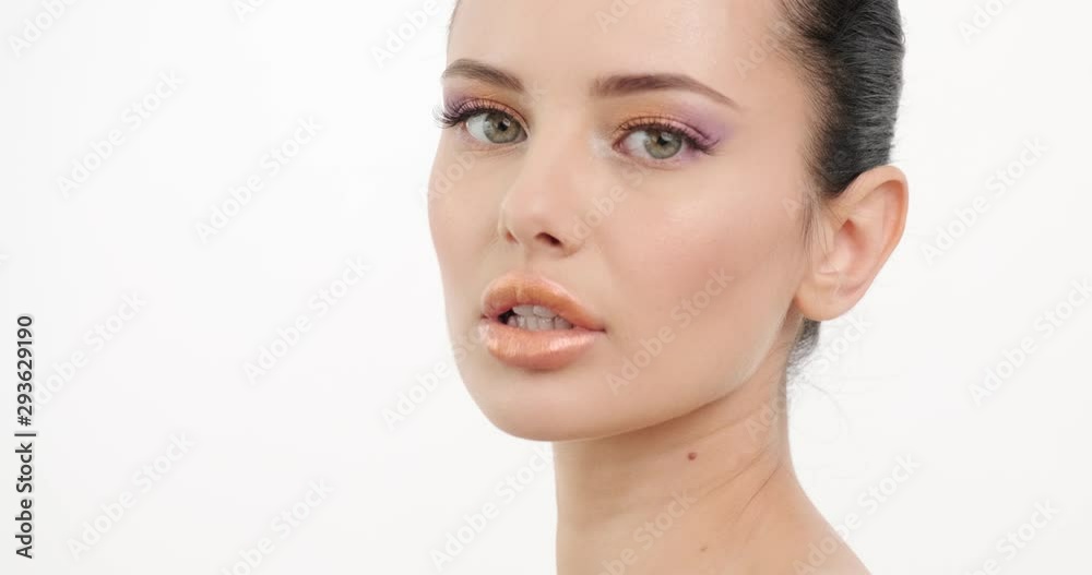 Beautiful girl with a sexy look turns to camera. Closeup portrait of a fashion model with orange makeup. Closeup face of young woman with clean skin of a face. Healthy woman with fresh skin of face