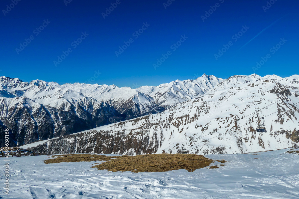 A beautiful and serene landscape of mountains covered with snow. Thick snow covers the slopes. Clear weather. Sharp slopes of the mountains covered with snow, with partially visible rocks.
