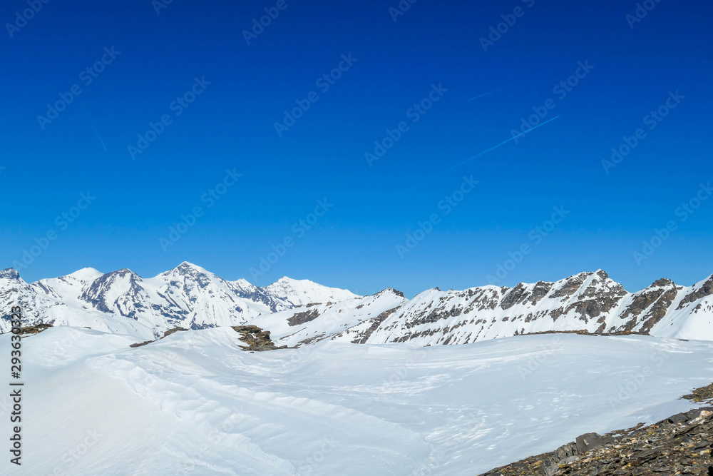 A beautiful and serene landscape of mountains covered with snow. Thick snow covers the slopes. Clear weather. Sharp slopes of the mountains covered with snow, with partially visible rocks. A beautiful and serene landscape of mountains covered with snow. Thick snow covers the slopes. Clear weather. Sharp slopes of the mountains covered with snow, with partially visible rocks.