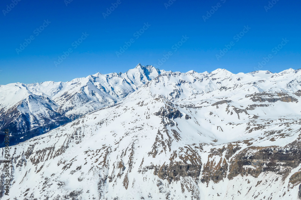 A beautiful and serene landscape of mountains covered with snow. Thick snow covers the slopes. Clear weather. Sharp slopes of the mountains covered with snow, with partially visible rocks.