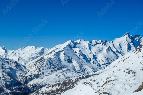 A beautiful and serene landscape of mountains covered with snow. Thick snow covers the slopes. Clear weather. Sharp slopes of the mountains covered with snow  with partially visible rocks.