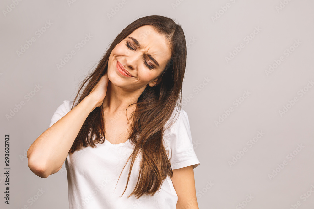 Tired young woman having pain in the neck isolated over grey background. Tired young woman having pain in the neck isolated over grey background.