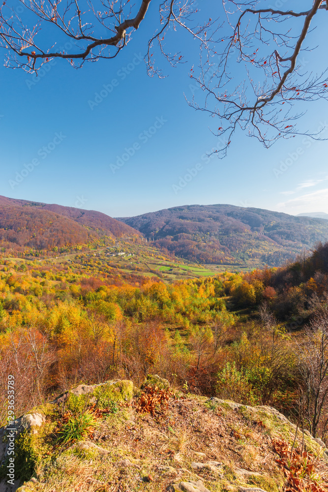 autumn scenery in mountains on a sunny day. view from a high vantage point in to the distant valley. trees in colorful foliage. rail station and viaduct in the distance. abandoned place