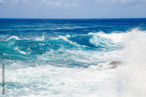 Waves and foam on surface of blue turquoise ocean water after storm, natural background
