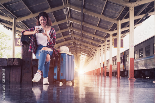 Asian young traveler woman with luggage looking at the camera while waiting train on railway platform