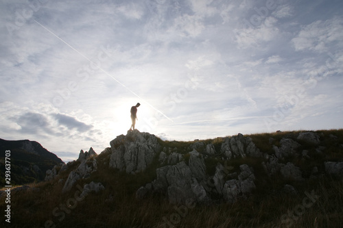 Young athletic man standing on the ridge. Trail running preparations for race.