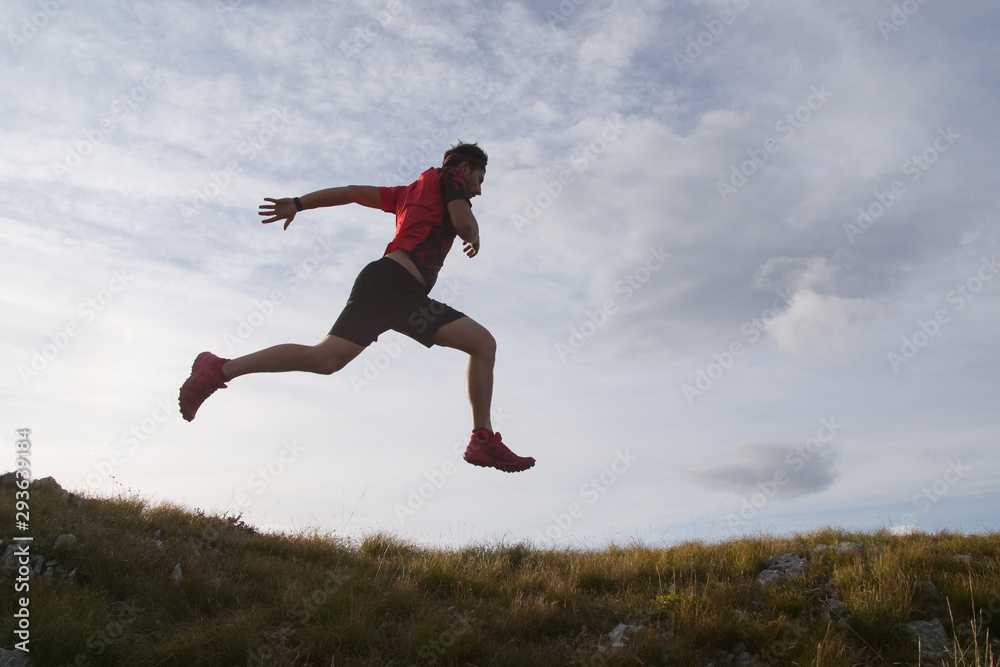 Trail running man jumping in the sky