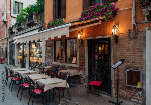 Fototapeta Naklejka Na Ścianę i Meble -  Old street with tables of restaurant in Venice, Italy. Architecture and landmark of Venice. Cozy cityscape of Venice.