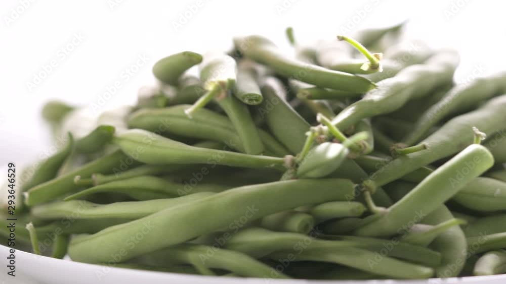 Fresh raw green beans on a plate rotating close-up. Fresh raw green beans on a plate rotating close-up.