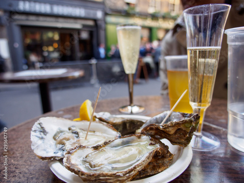 Photo Wide closeup of a plate of raw oysters served with sparkling Prosecco wine outdoors at Borough Market