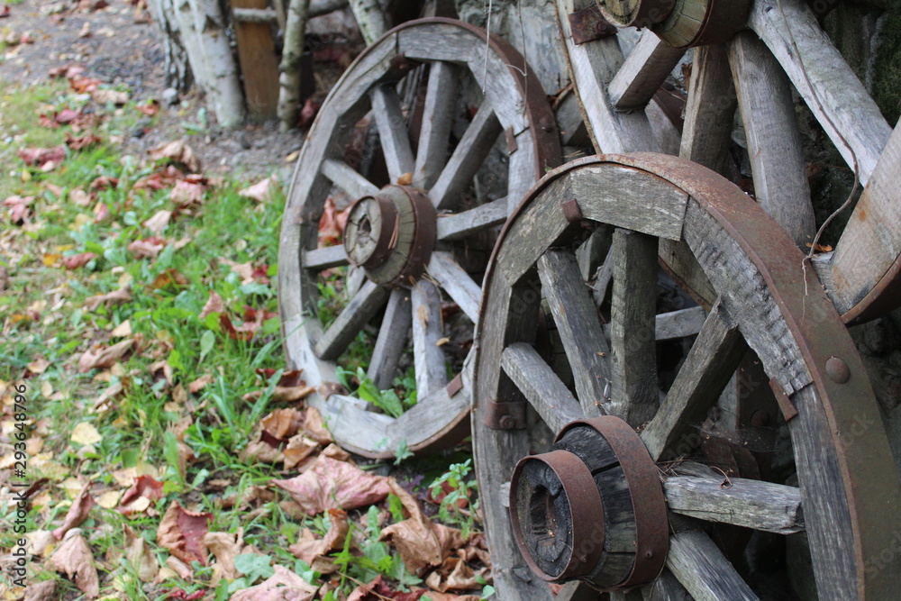 photo of old wheel from truck. the subject of wood.the wheel rim is metal.the spokes are wooden.