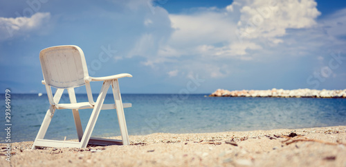 Fototapeta Naklejka Na Ścianę i Meble -  Empty beach chair by the sea with stormy clouds in the background