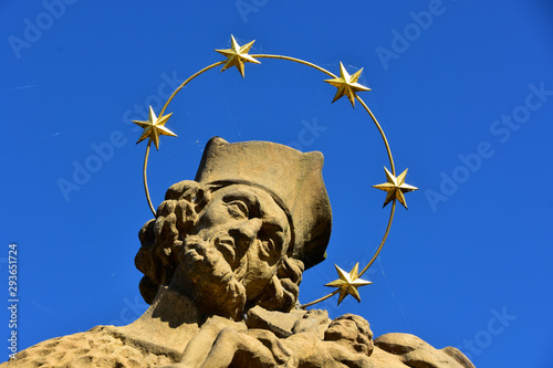 Detail of baroque stone Saint Nepomuk Statue with a stars crown on stone bridge, Czech Republic, sunny day with blue sky