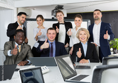 Group of international business people holding thums up in office photo