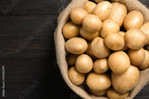 Raw fresh organic potatoes on black wooden background, top view. Space for text