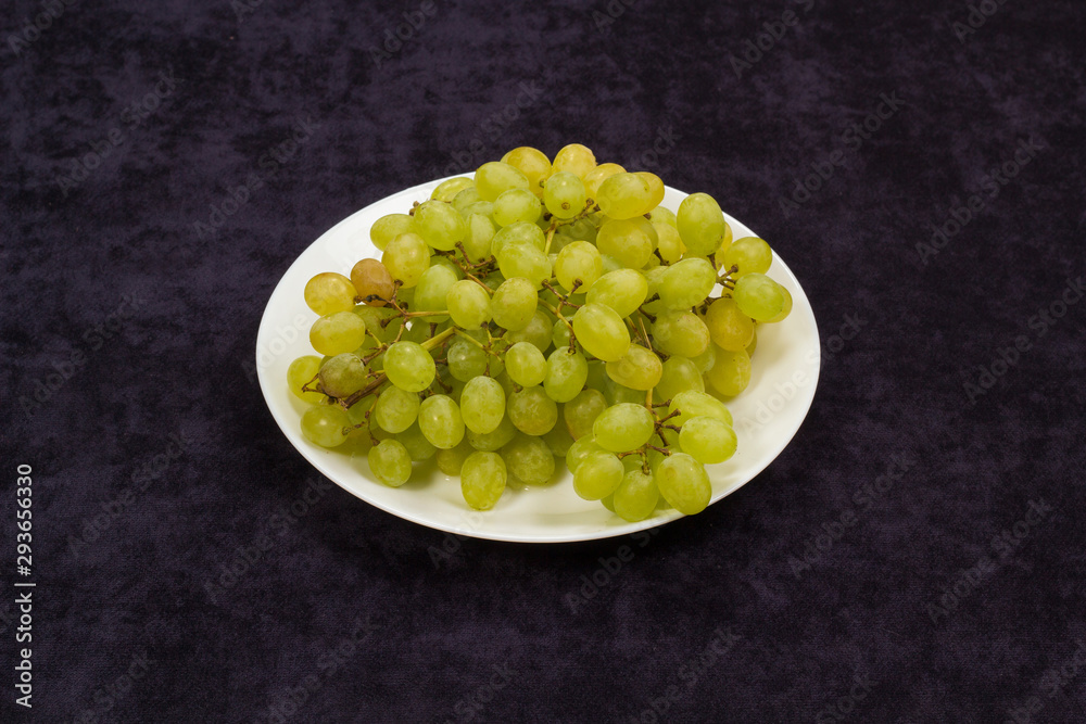 Still life grapes on a plate on a blue background Still life grapes on a plate on a blue background