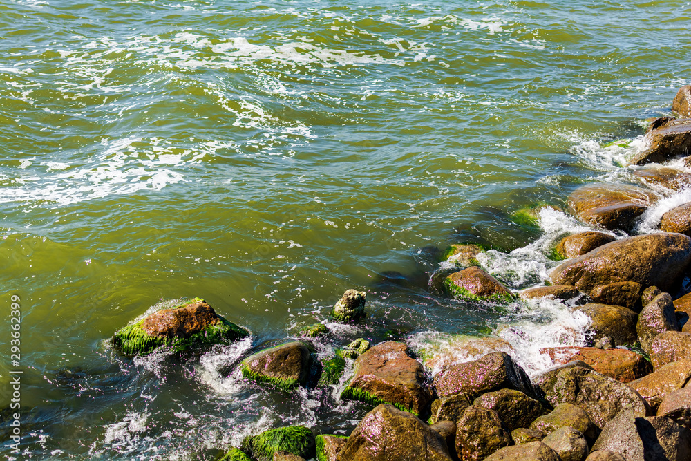 Close-up of a breakwater made of giant boulders, Baltic sea, in Palanga, Lithuania, Europe. Green Baltic sea water breaking on the stone groyne.