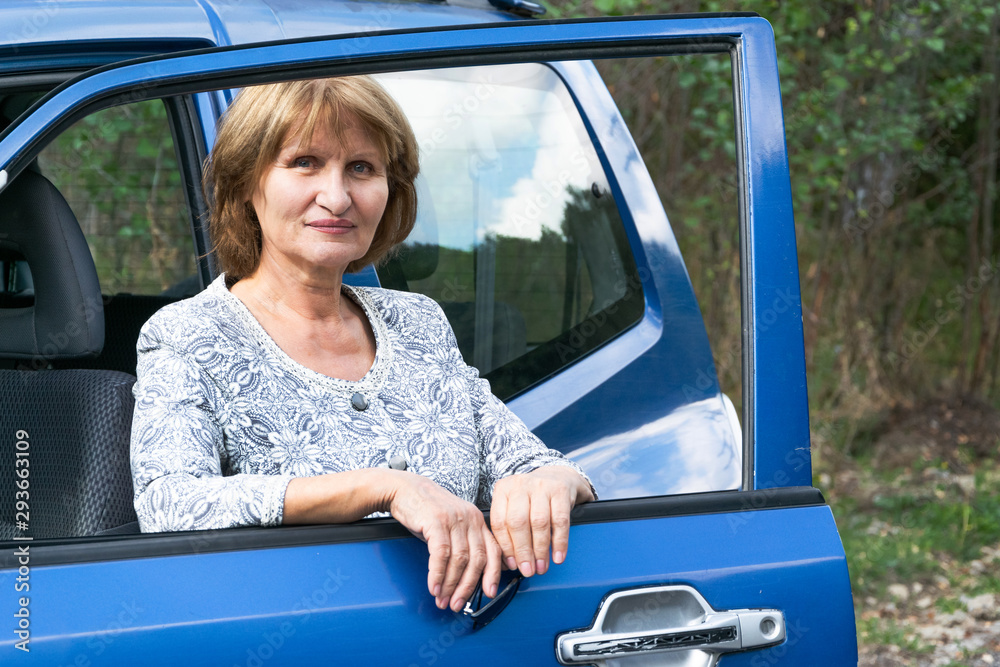 Naklejka premium Attractive senior lady traveling with automobile. Active lifestyle concept