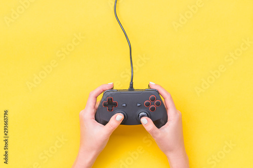 Hands Holding Gamepad. Black joysticks on yellow background. Computer game competition. Gaming concept. Place for text. Flat lay, top view, copy space.
