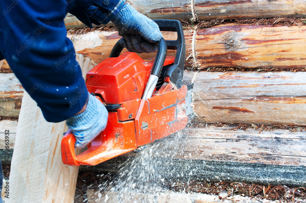man saws log for home with a chainsaw man saws log for home with a chainsaw
