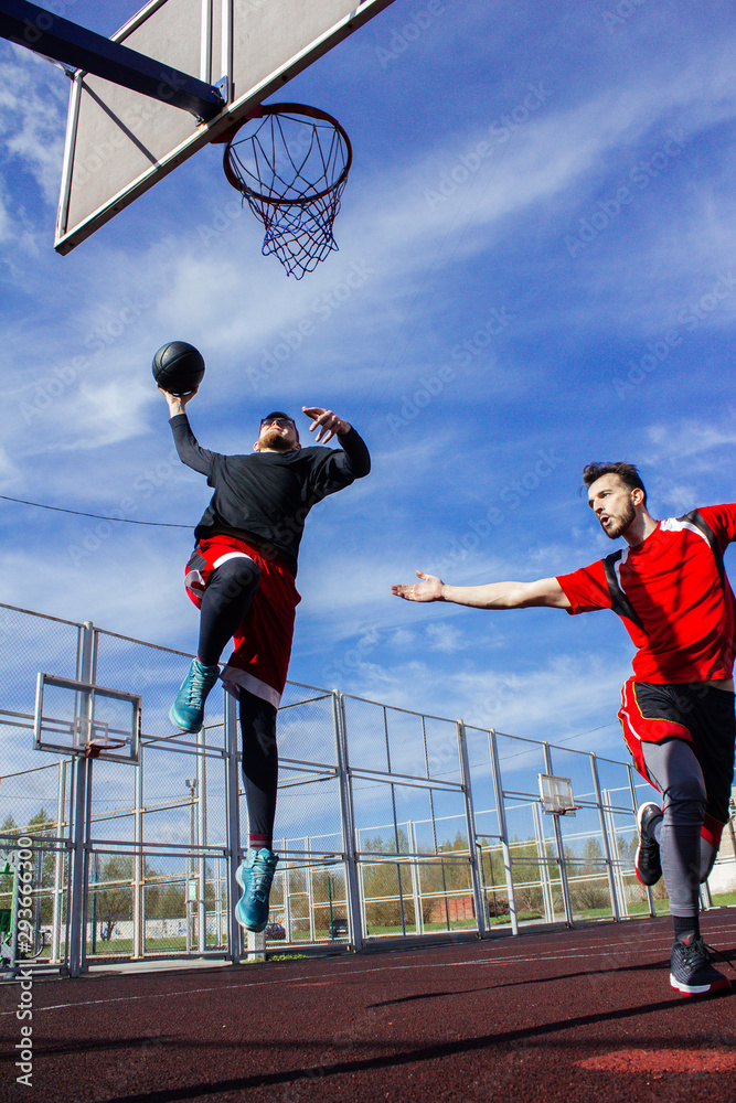 Teamwork, two basketball players play a throw. One athlete makes a pass, and the second performs a dunk in a basketball basket in a jump. Combination and rally. Basketball game, attack.