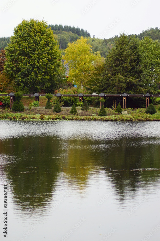 Fototapeta premium Der Kurpark von Weiskirchen im Saarland Deutschland mit einem See und überdachter Holzbrücke