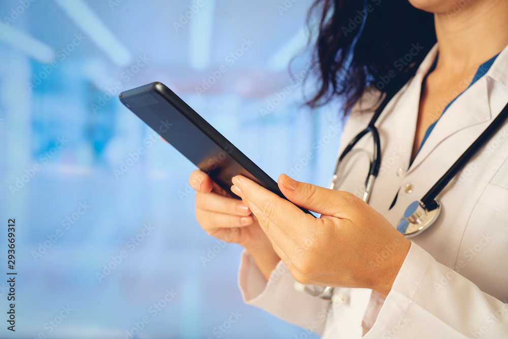 Woman doctor using tablet computer while standing straight in hospital Woman doctor using tablet computer while standing straight in hospital