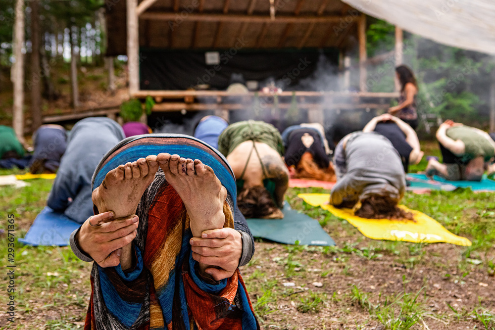 Diverse people enjoy spiritual gathering A view from the back of a barefooted person with muddy feet during an outdoor meditation workshop in nature during a woodland retreat.