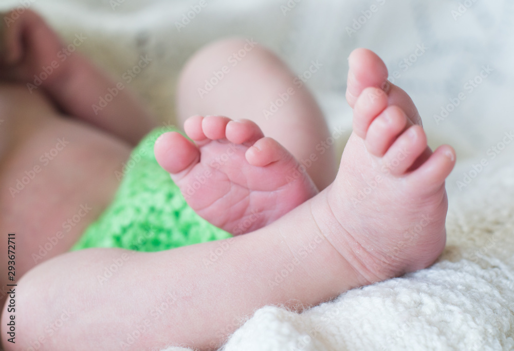 Newborn baby lies on a plaid. The feet of a newborn baby.