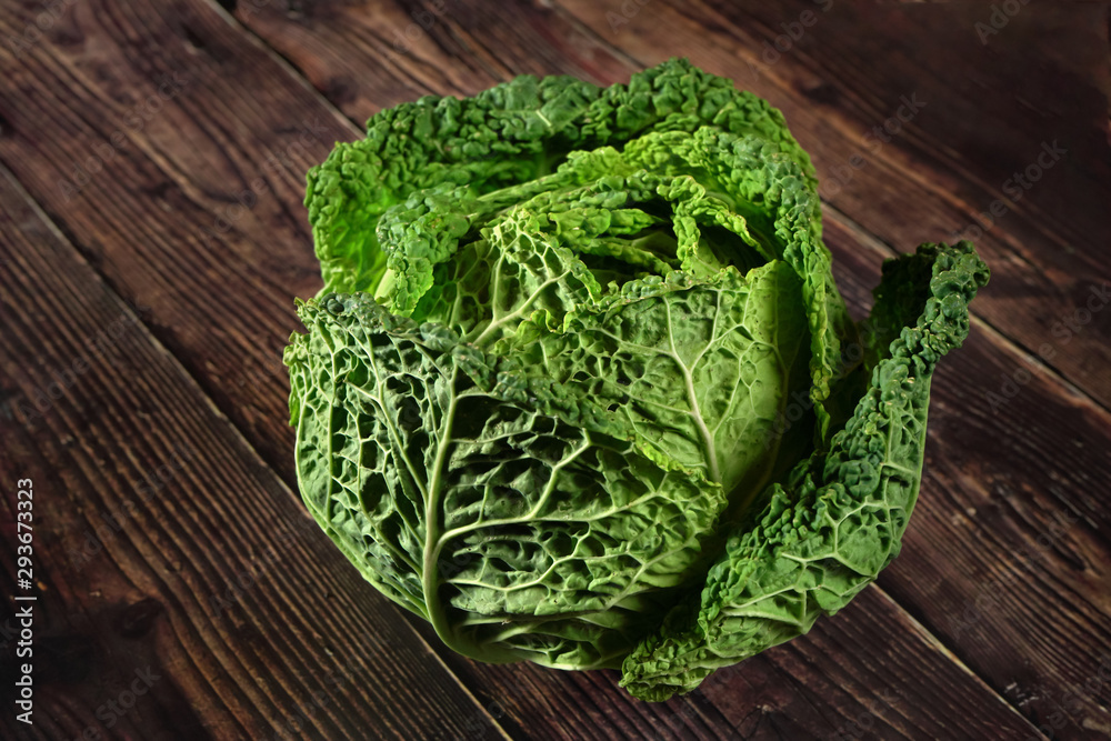 Green savoy cabbage head on dark wooden board Green savoy cabbage head on dark wooden board