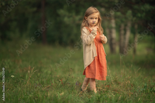 Full Length shot of girl sniffing flower in the hands and looking at the camera in the green park