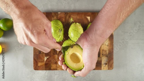 Cutting avocado in pieces on a wooden plank photo