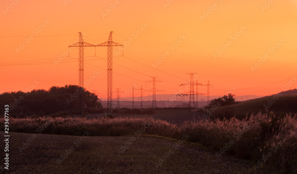 Silhouette electricity pole, electricity pylons technology on sunset time background, Ceske Stredohori, Czechia