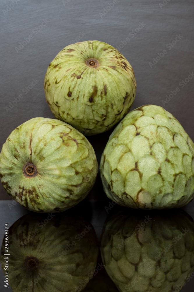 custard apple, tropical fruits on dar background with reflections