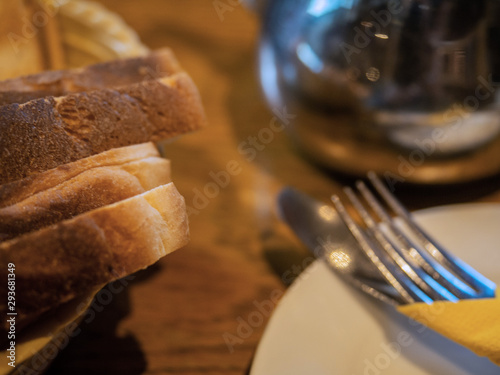 Table served for breakfast, Bread, white plates with cutlery and napkin on a wooden table in a pub. Selective focus.